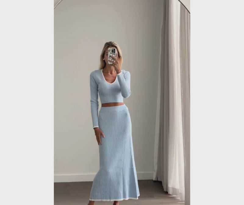 Female model online wearing baby blue knit crop top with matching high waist knit pleated maxi skirt  